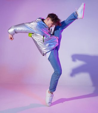 Havalı çocuk stüdyoda çağdaş dans ediyor. Neon ışıklı arka plan. Akrobatik bboy dansçısı. Break dans dersleri.