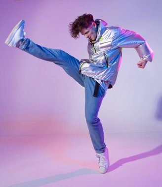 Havalı çocuk stüdyoda çağdaş dans ediyor. Neon ışıklı arka plan. Akrobatik bboy dansçısı. Break dans dersleri.