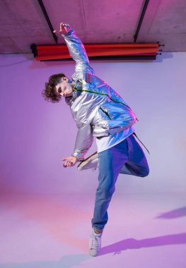Havalı çocuk stüdyoda çağdaş dans ediyor. Neon ışıklı arka plan. Akrobatik bboy dansçısı. Break dans dersleri.