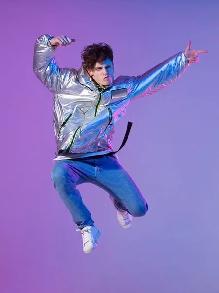 Cool guy dancing contemporary dance in studio. Neon light background. Acrobatic bboy dancer. Break dance lessons.