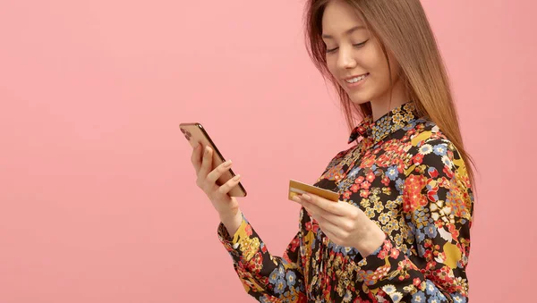 Meisje krijgt bankdienst, een online aankoop, met behulp van een creditcard met een studentenaanbod, houdt een mobiele telefoon in handen. — Stockfoto