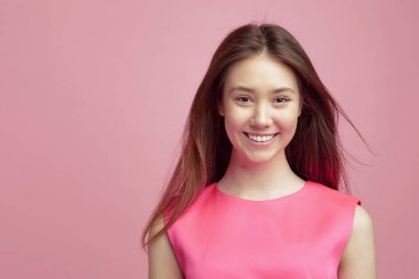 Güzel görünümlü genç bir kız şefkatle gülümsüyor. Beyaz dişli bir gülümseme. Saçlar rüzgarda savruluyor..