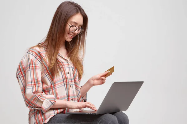 Linda joven estudiante llena los datos de la tarjeta de crédito en un ordenador portátil, para el pago en línea en una tienda en línea . — Foto de Stock
