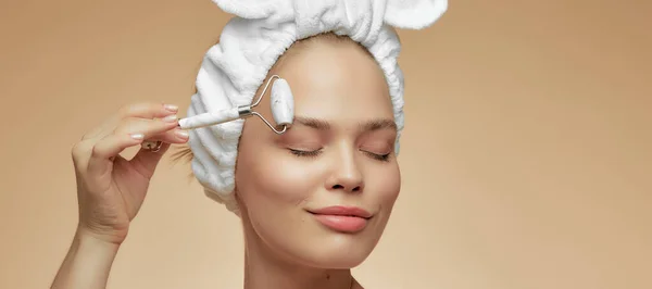 Όμορφη κοπέλα κάνει ένα μασάζ προσώπου gua sha ζαντ χαλαζία κύλινδρο, για την επίδραση της αναζωογόνησης του δέρματος. Διαδικασία στο σπίτι — Φωτογραφία Αρχείου