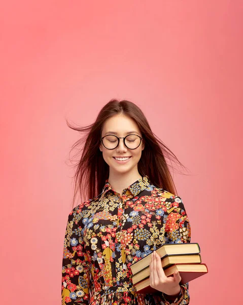 A young pretty girl student, with books from the library, smiling sweetly. Distance learning of foreign languages.