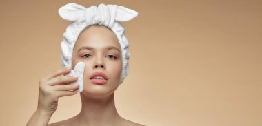 Masaj için gua Sha Quartz taşı olan güzel bir kız. Bej arka plan izole edilmiş. Kozmetik doğal eğilim.