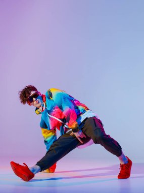 Stüdyoda çağdaş dans eden adam. Neon açık gri arka plan. Akrobatik bboy dansçısı. Break dans dersleri.