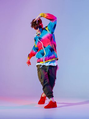 Stüdyoda çağdaş dans eden adam. Neon açık gri arka plan. Akrobatik bboy dansçısı. Break dans dersleri.