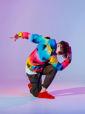 Stüdyoda çağdaş dans eden adam. Neon açık gri arka plan. Akrobatik bboy dansçısı. Break dans dersleri.