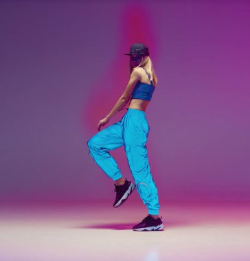 Yansıtıcı pantolonla, beysbol şapkasıyla neon ışıklı bir stüdyoda hip hop yapan tatlı bir genç kız. Dans rengi posteri.