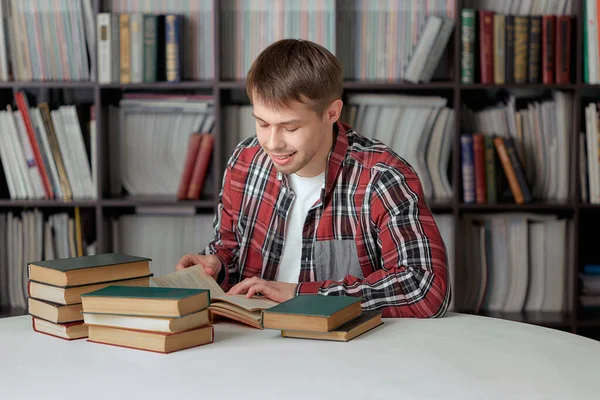 Un student cool în haine casual, citind literatură în biblioteca Universității pentru a se pregăti pentru examen . — Fotografie, imagine de stoc