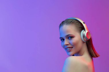 Kablosuz kulaklıklı güzel bir genç kız neşeli bir şekilde şarkı dinler. parlak renkli müzik afişi.
