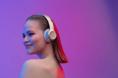 Kablosuz kulaklıklı güzel bir genç kız neşeli bir şekilde şarkı dinler. parlak renkli müzik afişi.