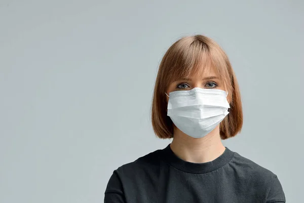 Портрет молодой девушки в хирургической маске, черная футболка на сером фоне. Остановите вирусный плакат . — стоковое фото
