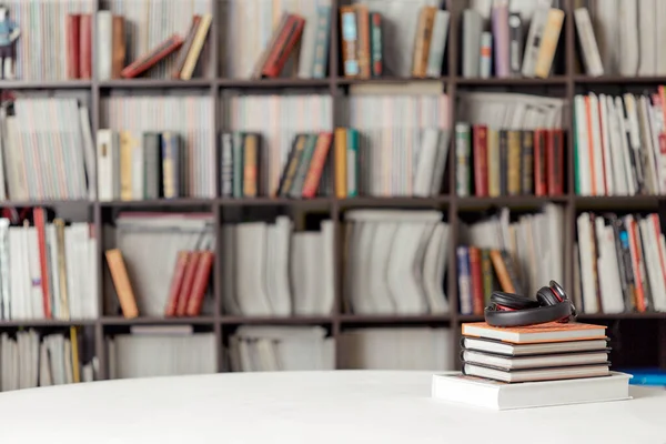 Una pila de libros con auriculares en el fondo de un estante de libros en la sala de lectura de la biblioteca. Cartel del estudiante —  Fotos de Stock