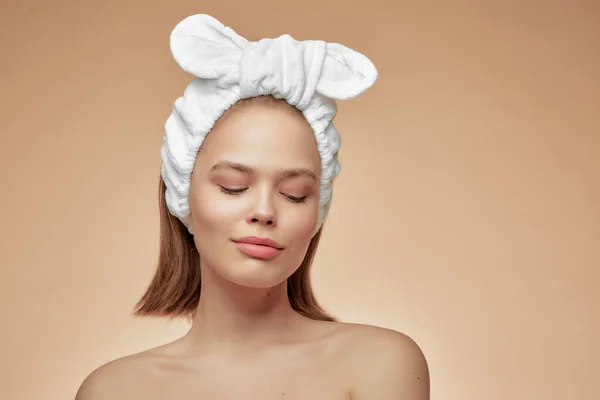 Uma jovem menina bonita em uma bandagem, sorrindo com os olhos fechados e ombros nus. Cartaz publicitário para cosméticos . — Fotografia de Stock