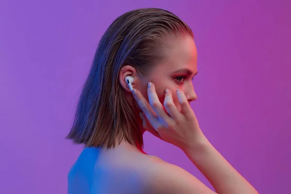 Egy gyönyörű fiatal lány vezeték nélküli fülhallgatóban jó hangulatban hallgatja a dalt. fényes színes zenei poszter. — Stock Fotó