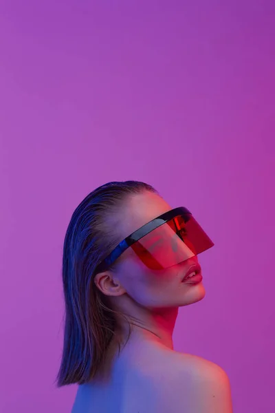 Cool snygg tjej med en fashionabel frisyr och snygga glasögon med ett stort glas poser på en ljus neon bakgrund. — Stockfoto