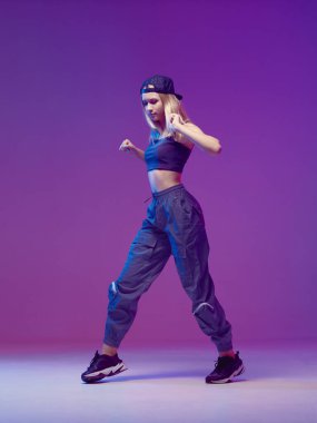 Stüdyoda neon ışıklı, şık kıyafetlerle hip-hop yapan, beysbol şapkası takan hoş bir genç kız. Dans rengi posteri.
