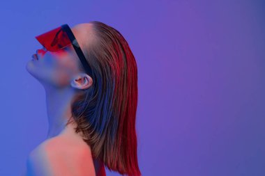 Şık bir saç stili ve parlak bir arka planda büyük cam pozlar veren şık gözlüklü havalı bir kız..