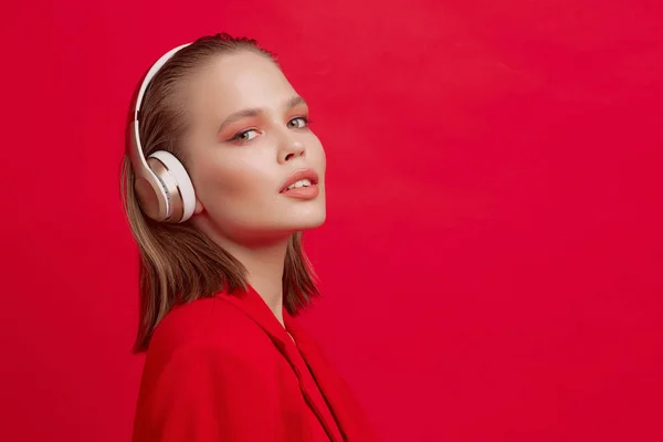 Ein schönes junges Mädchen mit drahtlosen Kopfhörern hört gut gelaunt Lieder. leuchtend buntes Musikposter. — Stockfoto