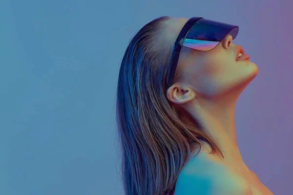 Cool elegáns lány egy divatos frizura és elegáns szemüveg egy nagy üveg pózol egy fényes neon háttér. — Stock Fotó
