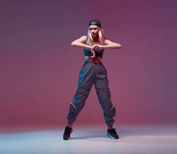 Nettes Teenie-Mädchen tanzt Hip-Hop in stylischer Kleidung, Baseballmütze, in einem Studio mit Neonbeleuchtung. Tanzfarbplakat. — Stockfoto
