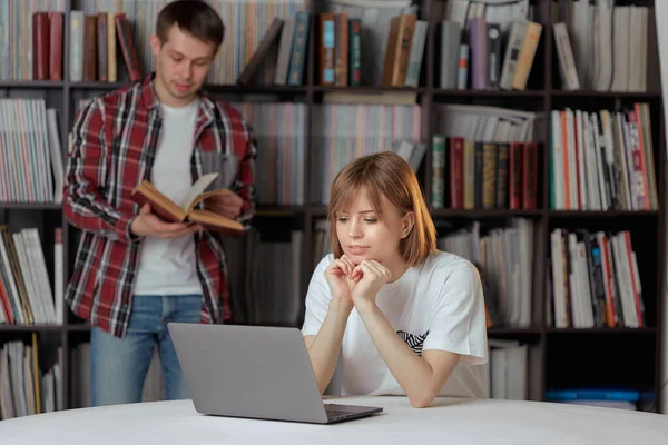 Drăguț băiat și fete studenți care lucrează la un proiect în biblioteca orașului, în căutarea de cărți și note de tastare pe un laptop . — Fotografie, imagine de stoc