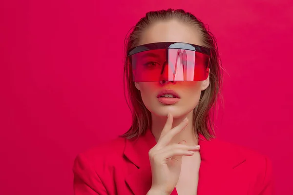 Chladná stylová dívka s módním účesem a stylovými brýlemi s velkým sklem pózuje na jasně červeném pozadí — Stock fotografie