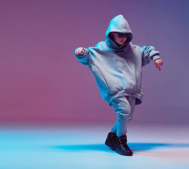 Kapüşonlu ve gözlüklü havalı çocuk, neon arka planda bir stüdyoda hip hop yapıyor..