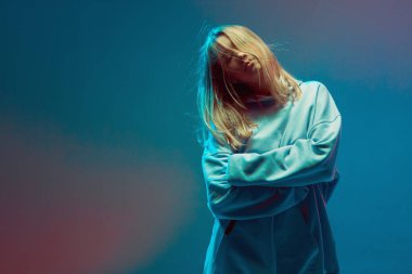 Havalı bir genç kızın portresi, kapüşonlu havalı poz, saçı uzamış, neon arka planda..