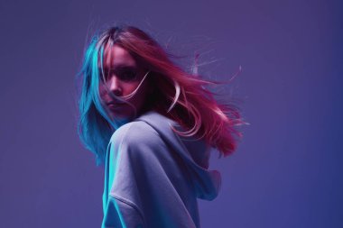 Havalı bir genç kızın portresi, kapüşonlu havalı poz, saçı uzamış, neon arka planda..