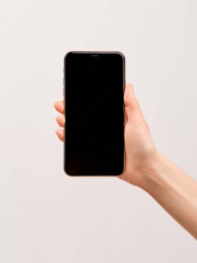 Beyaz arka planda zarif bir kızın elinde büyük boş bir ekranı olan modern bir akıllı telefon..