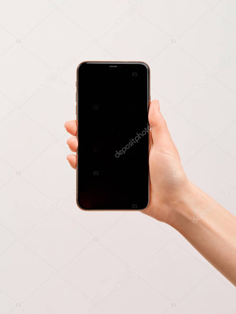 A modern smartphone with a large empty screen in the elegant hand of a girl on a white background.