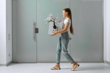 Genç ve güzel bir kız, kriz nedeniyle işten çıkarılıp kovulduktan sonra bir kutuda ofis malzemeleriyle yürüyor..