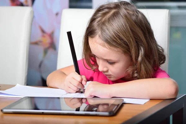 Маленькая девочка использует планшетный компьютер для домашнего задания — стоковое фото