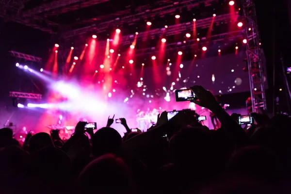 Rock konseri, mutlu insanların siluetleri el kaldırıyor.