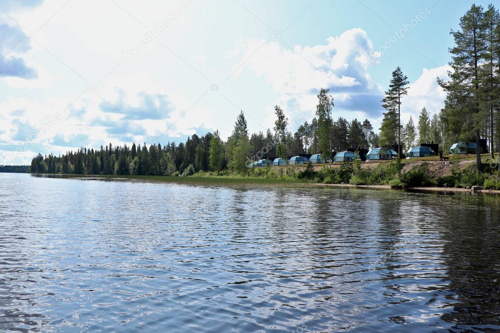 Cabins and trees on the shore of Lake Ranuanjarvi in Ranua, Finland on a hot summer day.
