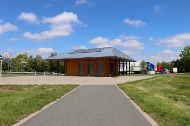 Bir bahar günü Almanya 'da otoban boyunca bir dinlenme alanının arkasında yarı kamyonlu tuvaletli bir binaya çıkan çimlerin yanında yürüyorum.. 