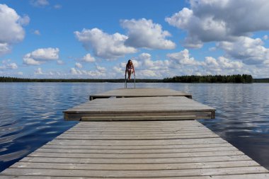 Genç kız (14 yaşında) Ranua, Lapland, Finlandiya 'daki Ranuanjarvi Gölü' ndeki ahşap bir iskelede merdivende oynuyor.. 