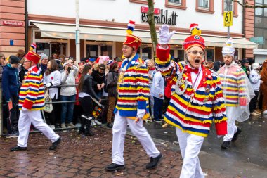 Mainz, Almanya 'daki Gül Pazartesi geçit töreninde parlak renkli kıyafetler giyen ve el sallayan adamlar..