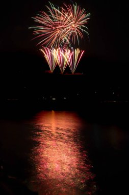 Almanya 'nın Koblenz kentinde düzenlenen yıllık bir etkinlikte, Ren nehrinde güzel bir yansıması olan kara gökyüzüne karşı çok renkli havai fişekler..