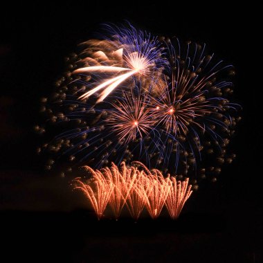 Almanya 'nın Koblenz kentindeki bir etkinlikte siyah gökyüzüne karşı altın ve mavi havai fişekler.