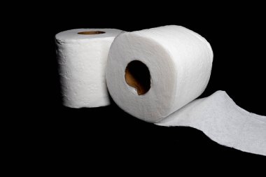Siyah arka plana karşı iki rulo beyaz tuvalet kağıdı..