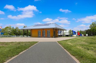 Güney Almanya 'da bir dinlenme alanındaki tuvaletlere giden kaldırım. Binanın arkasındaki otoparka kamyonlar park edilmiş..