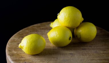 Ahşap masada siyah arka planı olan taze limonlar.