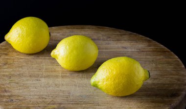 Ahşap masada siyah arka planı olan taze limonlar.