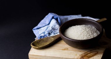 Kil kasede pişmemiş pirinç. Ahşap bir masada, siyah arka planda..