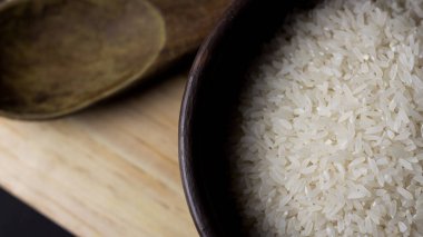 Kil kasede pişmemiş pirinç. Ahşap bir masada, siyah arka planda..