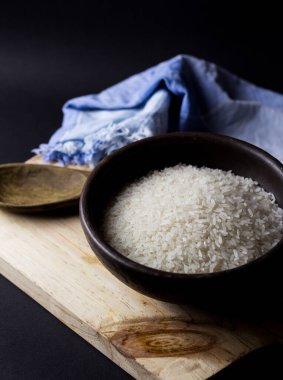 Kil kasede pişmemiş pirinç. Ahşap bir masada, siyah arka planda..